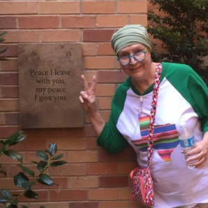 Janice Boyd standing next to a sign that says, "Peace I leave with you, my peace I give you."