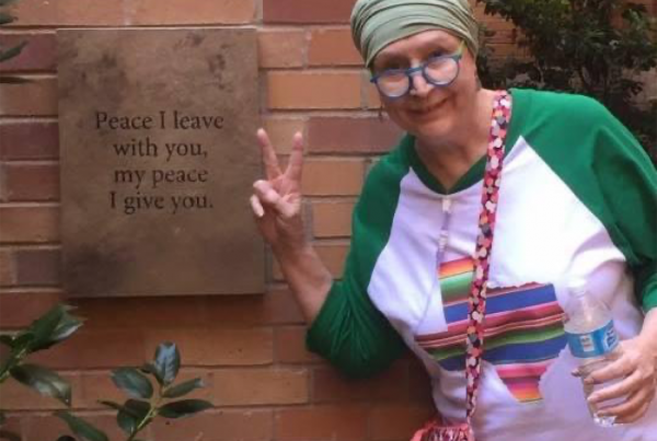 Janice Boyd standing next to a sign that says, "Peace I leave with you, my peace I give you."