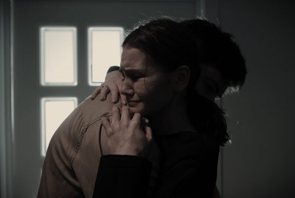 Image of a crying woman hugging a man. This is meant to symbolize a tumultuous romantic rekationship where domestic abuse is present.