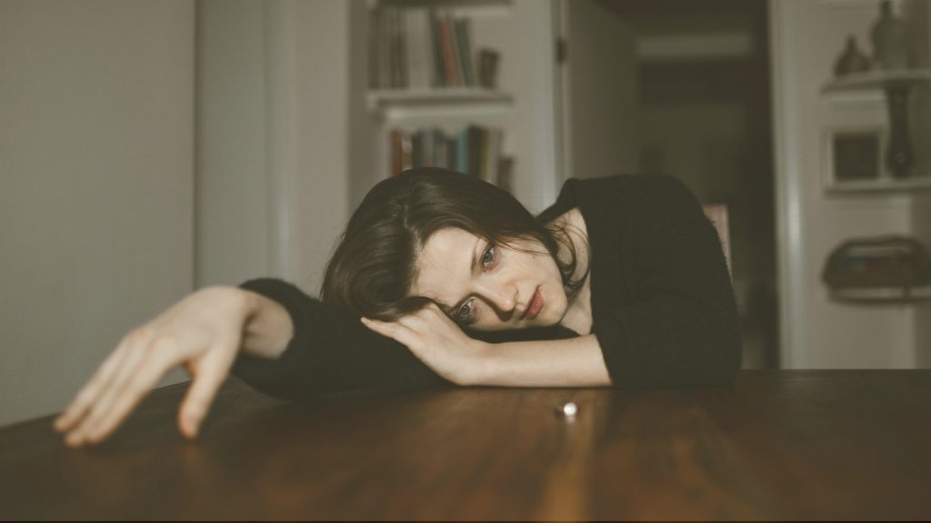 Image of a woman laying on a table, looking sad. Meant to symbolize how someone might feel in a toxic relationship.
